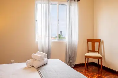 a room with a bed with a window and a chair at Villa Serrão, By OP in Ponta Delgada