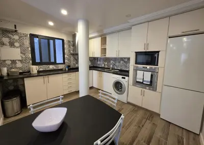 a kitchen with a table and a white refrigerator at Casa Dourada in Câmara de Lobos