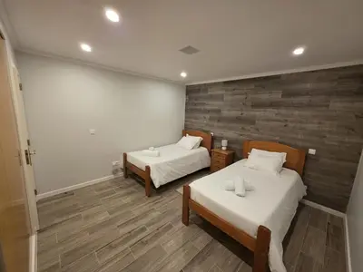 two beds in a room with wooden floors at Casa Dourada in Câmara de Lobos
