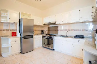 a kitchen with white cabinets and a stainless steel refrigerator at Mill House in Ponta do Sol