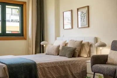 a bedroom with a bed with pillows and a chair at SUPER Anadia - Vintage in Funchal