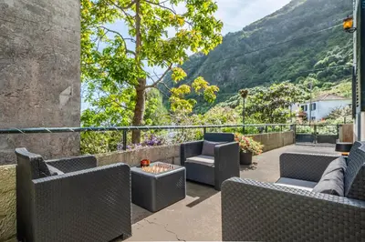 a patio with chairs and tables with mountains in the background at SUPER Zen in Ponta Delgada