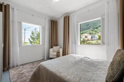 a bedroom with a bed and two windows at SUPER Zen in Ponta Delgada