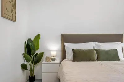 a bedroom with white walls and a bed with green pillows at SUPER Zen in Ponta Delgada