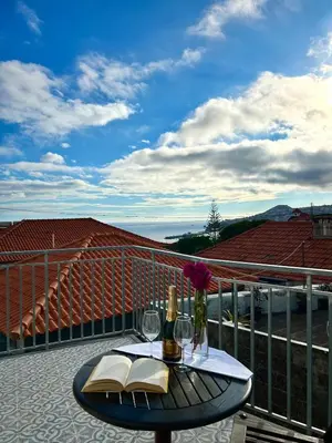 a table with a bottle of wine and books on a balcony at Casa Happy in Funchal