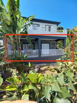 a house on the beach with plants in the foreground at Maresia Gardens in Porto da Cruz