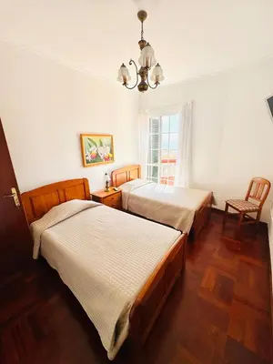 a bedroom with two beds and a chandelier at Casa da Rochinha in Santa Cruz