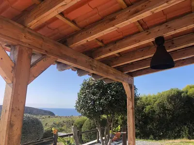 a wooden pergola with a bell hanging from it at CasaDaMeiaLuaArrifana in Aljezur