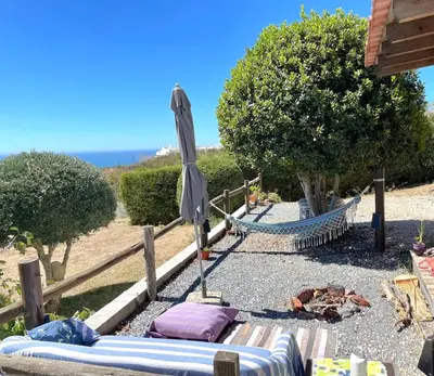 a hammock and an umbrella on a beach at CasaDaMeiaLuaArrifana in Aljezur