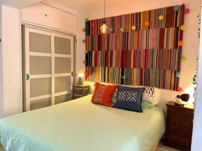 a bedroom with a bed with colorful pillows on it at CasaDaMeiaLuaArrifana in Aljezur