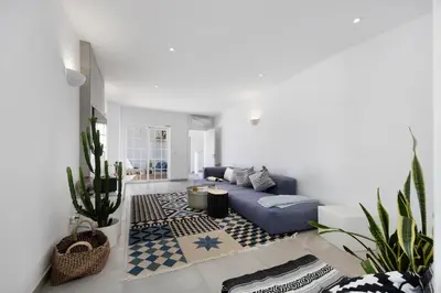 a living room with a blue couch and a rug at Casa Surfer’s Sanctuary - Algarve in Vila do Bispo