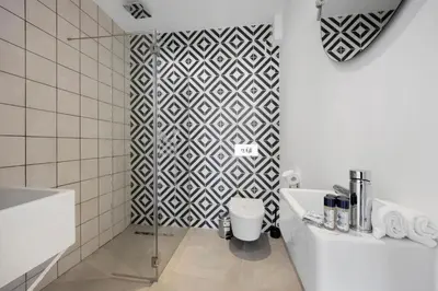 a bathroom with a black and white tiled wall at Casa Surfer’s Sanctuary - Algarve in Vila do Bispo