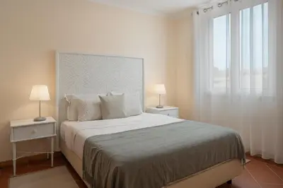 a bedroom with a bed and a window and a chair at Casa Encosta do Sol by An Island Apart in Porto Santo