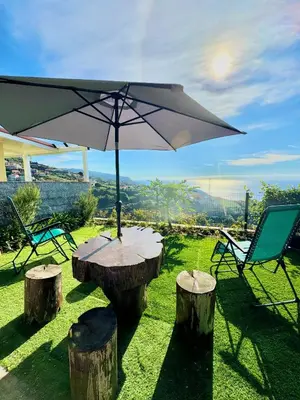 a table with an umbrella on top of some logs at Hera House, Ponta do Sol, Portugal in Canhas