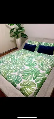 a bed with a green and white comforter and blue pillows at Forum Palace Madeira in Funchal