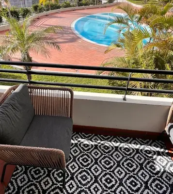 a balcony with a chair and a swimming pool at Forum Palace Madeira in Funchal