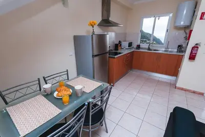 a kitchen with a table and a refrigerator at Cozy Private Apartment Calheta in Arco da Calheta