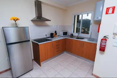 a kitchen with wooden cabinets and a stainless steel refrigerator at Cozy Private Apartment Calheta in Arco da Calheta