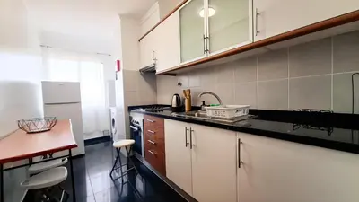 a kitchen with white cabinets and a black counter top at Mãe de Deus - Caniço - Madeira in Caniço