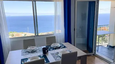 a dining room with a table with a view of the ocean at Mãe de Deus - Caniço - Madeira in Caniço