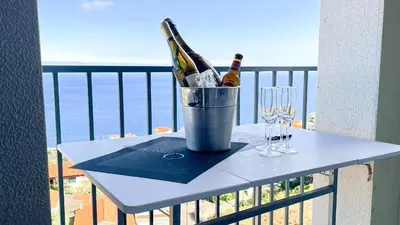 a table with two bottles and glasses on a balcony at Mãe de Deus - Caniço - Madeira in Caniço