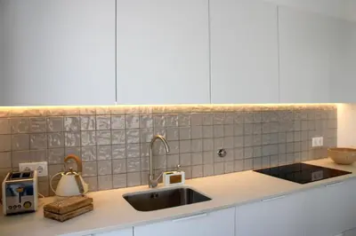 a kitchen counter with a sink and white cabinets at Casa Tonel in Bordeira