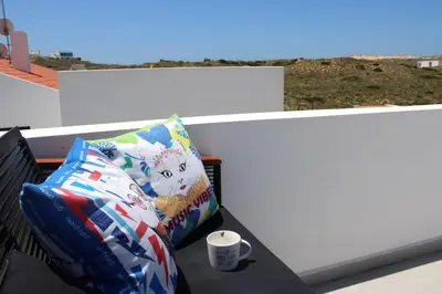 a pillow and a coffee cup sitting on a bench at Casa Tonel in Bordeira