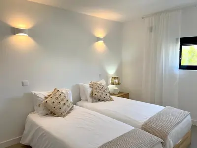 two beds in a bedroom with white walls at Casa Tonel in Bordeira