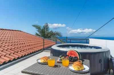 a table with food and drinks on a balcony with a hot tub at Casa dos Vinhos by Atlantic Holiday in Santa Maria Maior