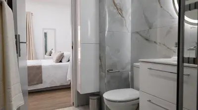 a bathroom with a toilet and a sink and a bed at Residential Camacho, By OP in Funchal