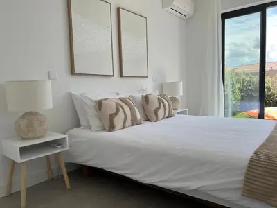 a white bedroom with a bed and a window at Casa Beliche in Aljezur