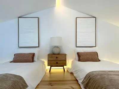 two twin beds in a room with two windows at Casa Beliche in Aljezur