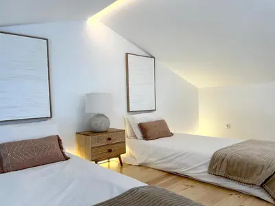 a bedroom with two beds and a table with a lamp at Casa Beliche in Aljezur