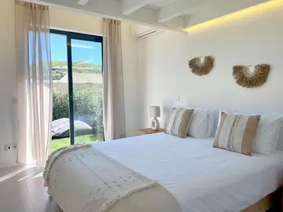 a bedroom with a white bed with a large window at Casa Telheiro in Aljezur