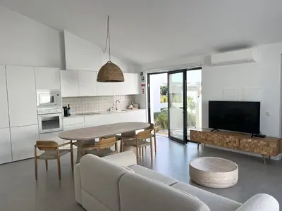 a kitchen and living room with a table and chairs at Casa Mareta in Bordeira