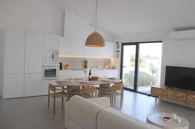 a kitchen and living room with a table and chairs at Casa Mareta in Bordeira
