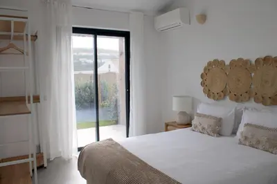 a white bedroom with a large bed and a window at Casa Mareta in Bordeira