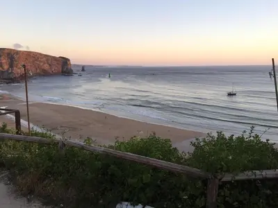 a beach with a wooden fence and the ocean at Arrifana - CASA DAS MARÉS - Casa na Praia in Aljezur