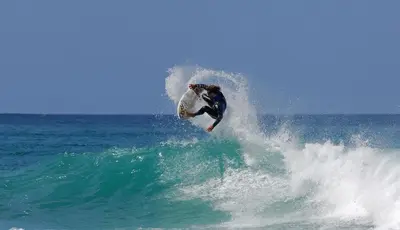 a man riding a wave on a surfboard in the ocean at Arrifana - CASA DAS MARÉS - Casa na Praia in Aljezur