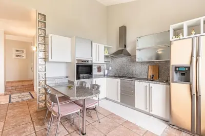 a kitchen with white cabinets and a table and chairs at Casa do Jardim Botanico in Faial