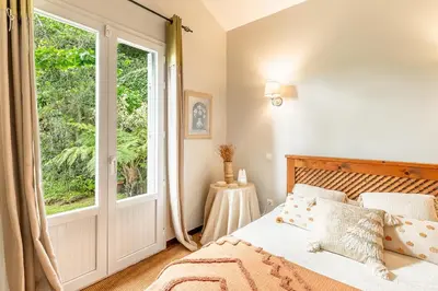 a bedroom with a bed and a large window at Casa do Jardim Botanico in Faial