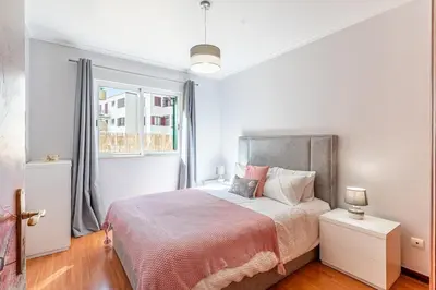 a white bedroom with a bed and a window at Cozy Stay in Caniço