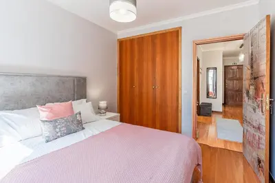 a bedroom with a large bed and a wooden door at Cozy Stay in Caniço