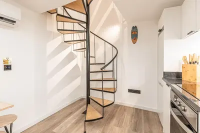 a spiral staircase in a kitchen with white walls at Yellow Wave in Paul do Mar