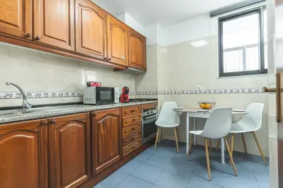 a kitchen with wooden cabinets and a table and chairs at Pena View Apartment by Atlantic Holiday in Funchal