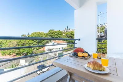 a table with food and drinks on a balcony at Pena View Apartment by Atlantic Holiday in Funchal
