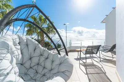 a white couch sitting on a balcony with chairs at Breeze House 1 by Atlantic Holiday in Caniço