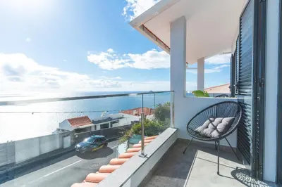 a balcony with a chair and a view of the water at Breeze House 1 by Atlantic Holiday in Caniço