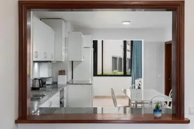 a kitchen with white cabinets and a table and chairs at Palmasol by An Island Apart in Calheta