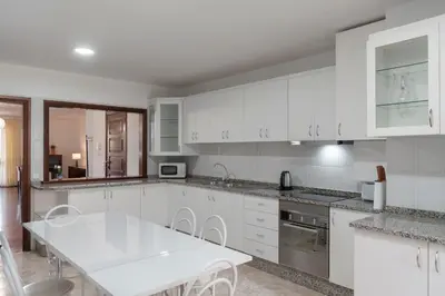 a kitchen with white cabinets and a white table at Palmasol by An Island Apart in Calheta